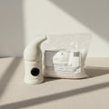 White ceramic pipe next to a bag of salt on a white background